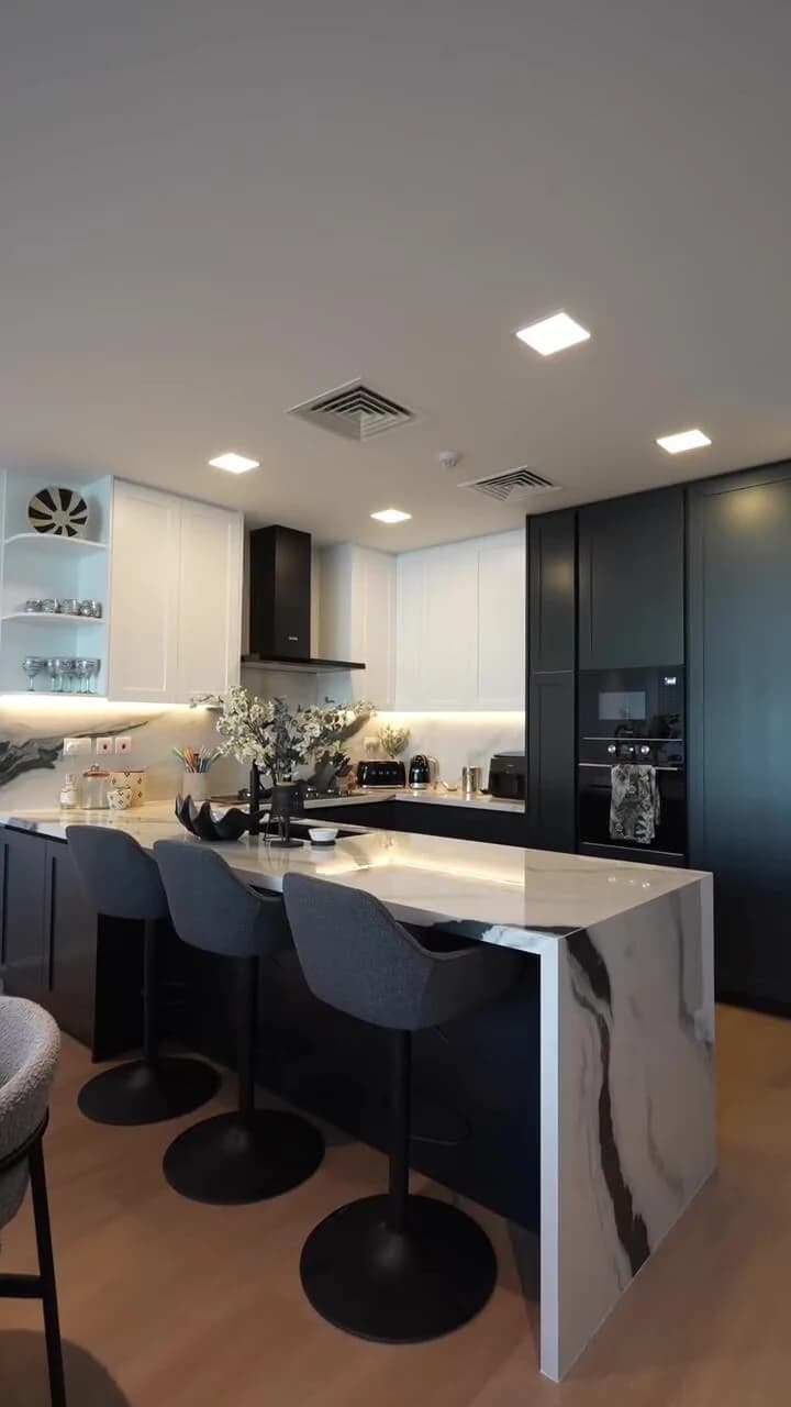 Black and white kitchen with marble waterfall island in Al Furjan