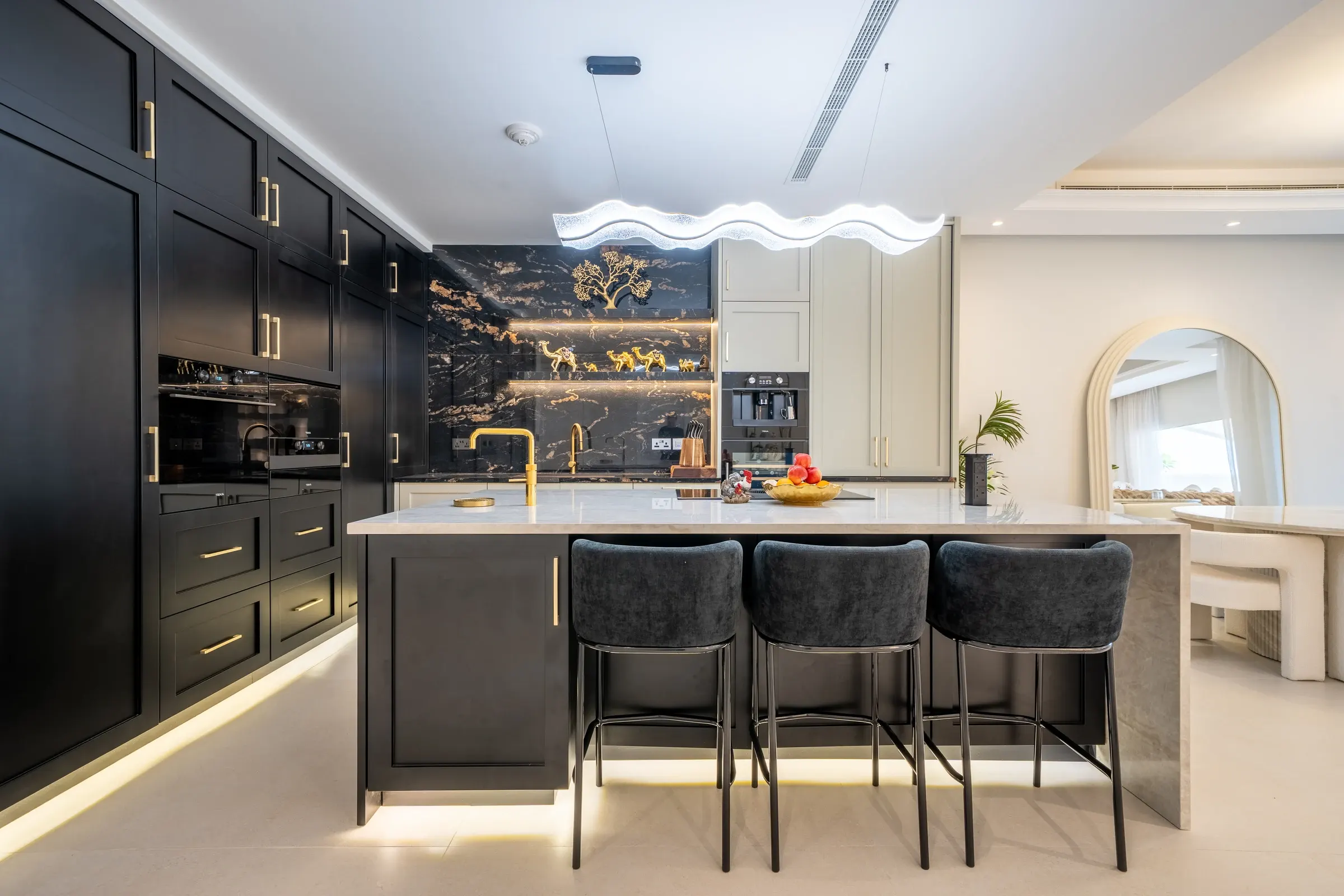 Dark luxury kitchen with gold hardware and marble backsplash by Vigilant Kitchens in a Jumeirah Golf Estates villa