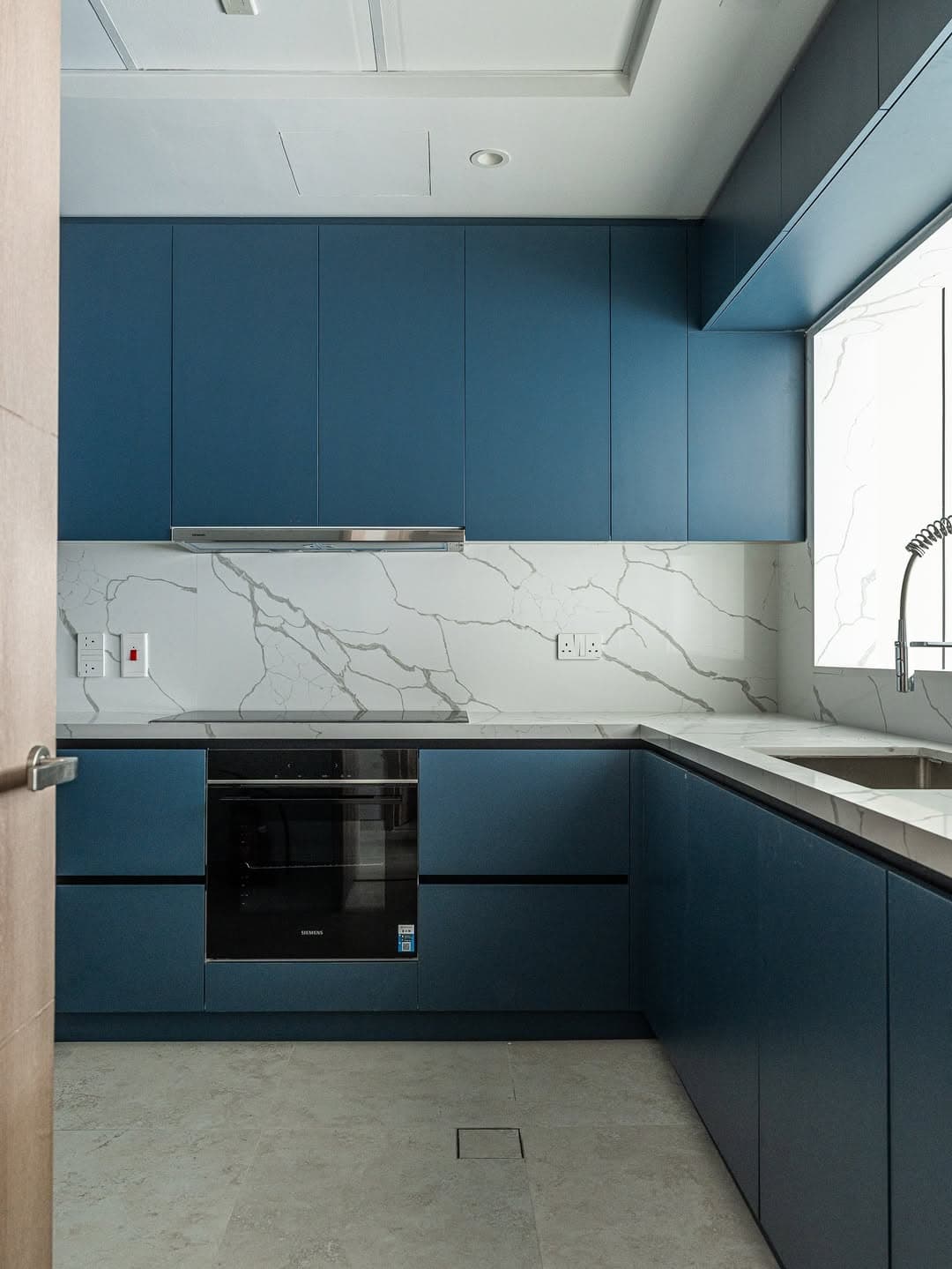 Deep teal cabinetry with marble backsplash in Emirates Hills